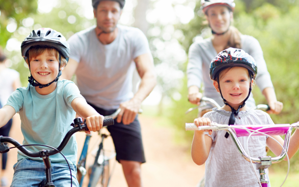 Two adults and two children riding toward the camera on bicycles