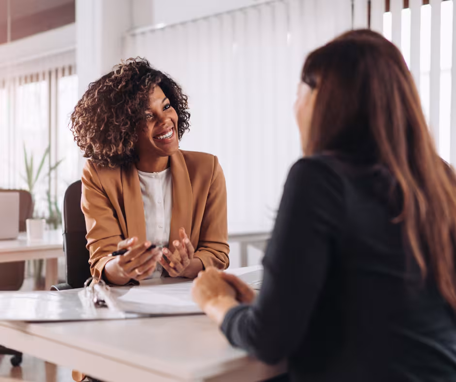 Two women discussing documents across a desk in a business setting